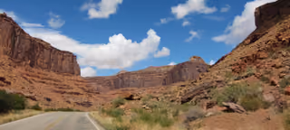 historic highway in Utah with red rocks, blue sky, and white clouds